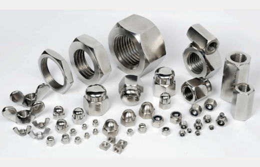 Variety of stainless steel nuts, wing nuts, acorn nuts, and hexagonal fasteners arranged on a white surface