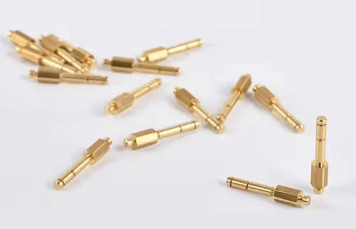 Small brass pins with hexagonal mid-sections scattered on a white background
